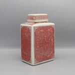 Un vase en céramique décoré de motifs asiatiques élégants et complexes dans des tons rouges et crème.
