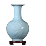 Vase de porcelaine blanc turquoise ornementé d'un motif artistique.
