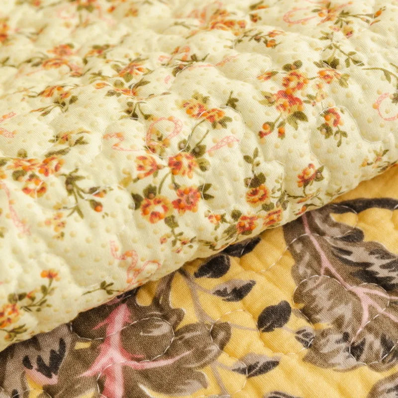 Gros plan d'un motif floral sur un tissu froissé, mêlant des petites fleurs blanches et orangées sur un fond jaune.