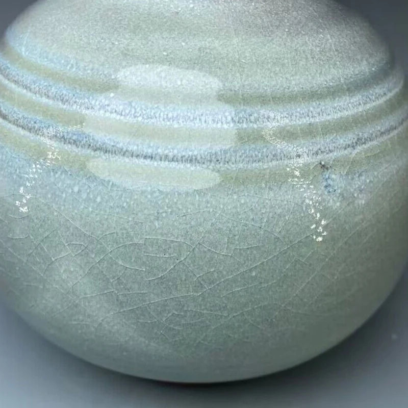 Pot en céramique blanc avec des motifs de vagues abstraites, créant une texture élégante et épurée.
