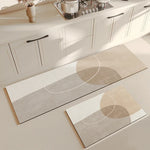 Deux tapis décoratifs beige et blanc ornés de formes géométriques, placés sur le sol d'une cuisine moderne avec des meubles blancs.
