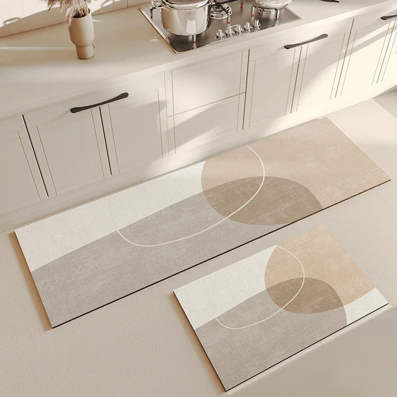 Deux tapis décoratifs beige et blanc ornés de formes géométriques, placés sur le sol d'une cuisine moderne avec des meubles blancs.