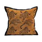 Coussin décoratif avec impression de léopards sur un fond doré.