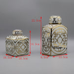 Deux vases décoratifs de formes et de motifs géométriques dorés et blancs.
