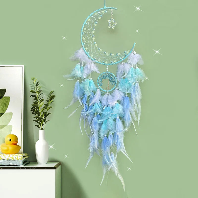 Capteur de rêves en forme de lune bleu et argent avec des plumes blanches et bleues qui pendent, décoré d'un ornement en forme d'étoile scintillante, placé sur une étagère avec des accessoires décoratifs.