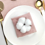 Un beau bouquet de coton blanc disposé élégamment sur un linge rose pâle, entouré d'ustensiles de cuisine dorés.