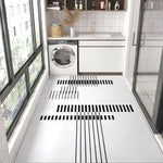 Une cuisine moderne avec une machine à laver et des éléments de décoration sur des étagères, avec un carrelage noir et blanc au sol créant un design géométrique élégant.
