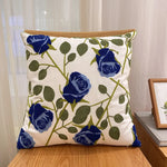 Coussin d'extérieur en lin orné de belles roses bleues et de feuilles vertes, créant un motif floral élégant.