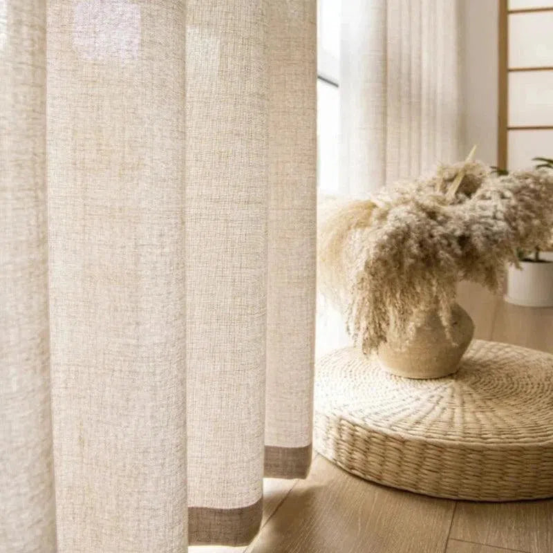 Image de rideaux élégants dans un intérieur moderne et épuré, avec une décoration naturelle comprenant un vase de fleurs séchées posé sur un tapis tressé. Idéal pour créer une ambiance chaleureuse et sereine dans votre espace de vie. Parfait pour ajouter une touche contemporaine à votre décor.
