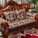 Un élégant canapé en cuir marron à l'allure classique, orné de magnifiques coussins floraux brodés et de franges élégantes, créant une atmosphère chaleureuse et invitante dans cette pièce d'intérieur.