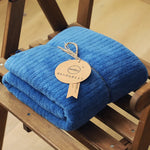 Une couverture bleue douce et moelleuse avec une étiquette en carton ornée d'un ruban attaché.