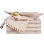 Serviettes de table beige en lin avec un anneau décoratif doré posées sur la pile.