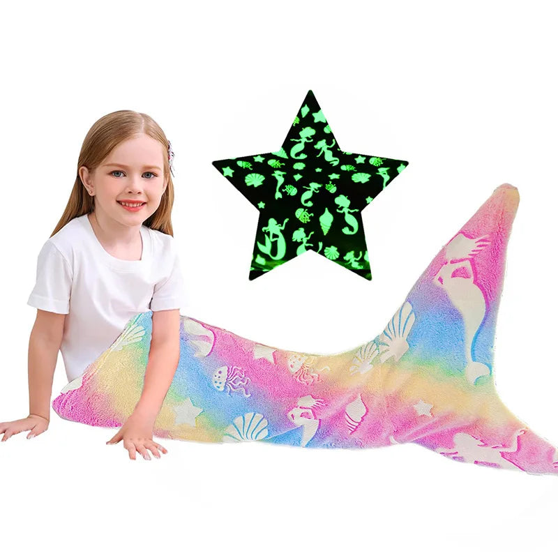 Une jeune fille souriante posant sur une queue de sirène multicolore et un grand pendentif en forme d'étoile ornée de motifs luminescents.