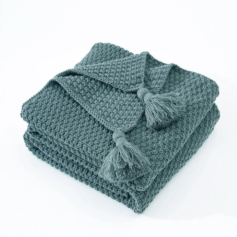 Couverture en tricot gris doux et douillet avec pompons décoratifs.