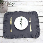 Cette image présente une assiette blanche avec des herbes vertes posée sur un set de table gris clair sur un fond en bois blanc.
