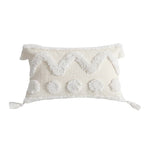 Taie d'oreiller rectangulaire blanche avec motifs texturés et pompons décoratifs.
