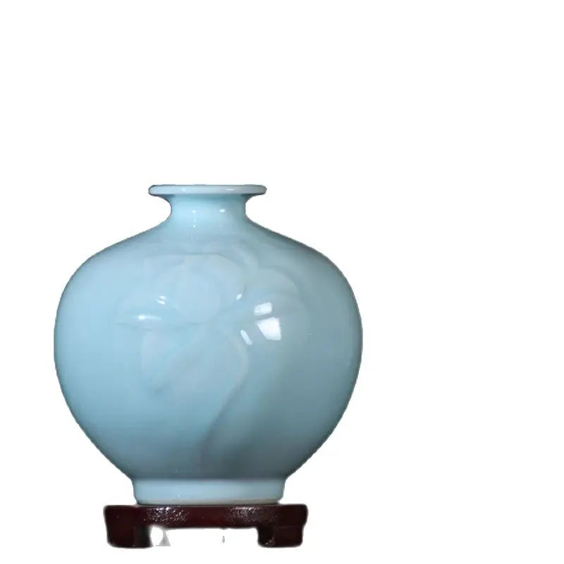 Vase de porcelaine bleu clair de forme sphérique sur un support en bois foncé.