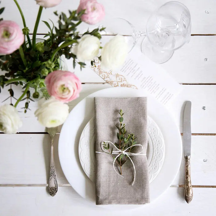 Une table élégamment dressée avec des fleurs fraîches, des verres cristallins et des couverts vintage, suggérant une atmosphère raffinée et conviviale.
