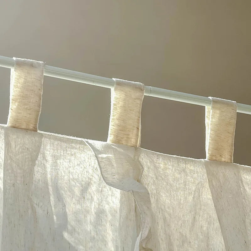 Rideaux en tissu beige, pendus à une tringle blanche dans une pièce à l'ambiance apaisante.