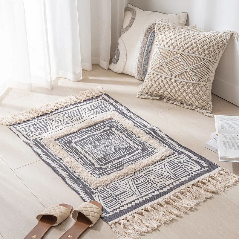 Tapis décoratif en macramé avec motifs géométriques et franges, accompagné de coussins assortis, créant une ambiance chaleureuse et harmonieuse dans cette pièce lumineuse.