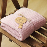 Une couverture moelleuse et douillette de couleur rose pâle, enrubannée d'une étiquette dorée.