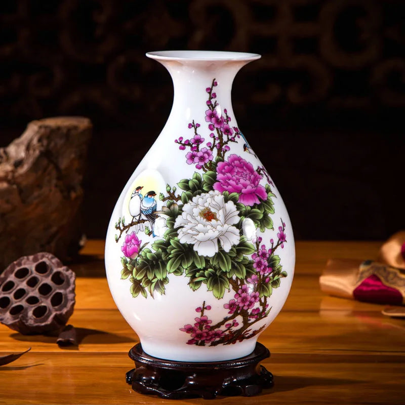 Un vase en porcelaine blanche décoré de fleurs de pivoines et de prunus en fleurs, ainsi que d'un oiseau, sur un socle en bois foncé.