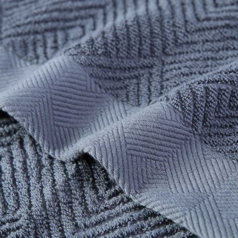 Gros plan d'un motif géométrique gris foncé et texturé sur un tissu.