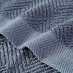 Gros plan d'un motif géométrique gris foncé et texturé sur un tissu.