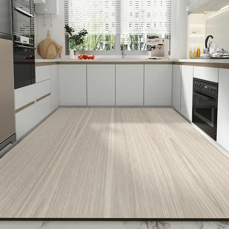L'image montre une cuisine moderne avec des armoires blanches, un évier avec robinet chromé, un plan de travail en bois clair, et un four encastré. Le sol est recouvert d'un revêtement en bois beige clair, créant une ambiance élégante et épurée.