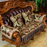 Un canapé en bois sculpté avec des ornements dorés, recouvert de coussins aux motifs floraux vintage.