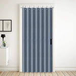 Rideau accordéon bleu gris installé dans une embrasure de porte, utilisé comme cloison souple pour séparer deux espaces de vie avec élégance.