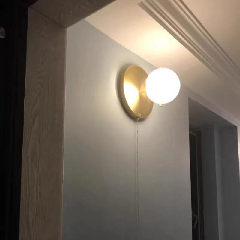 Applique murale boule laiton dans un couloir
