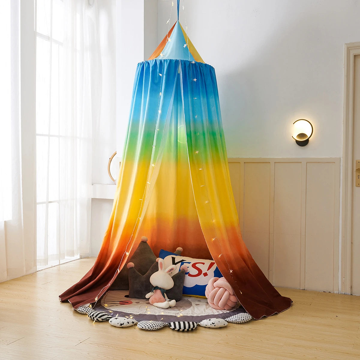 Lit enfant coloré et confortable avec ciel de lit étoilé, mobilier et jouets pour un espace de jeu et de repos accueillant.