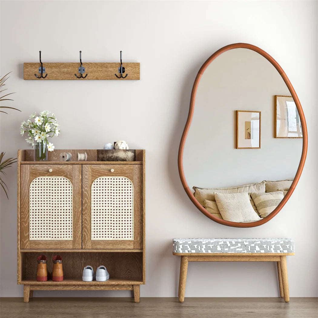 Meuble en bois avec miroir ovale, décoration florale et rangement pour chaussures dans un intérieur élégant et épuré.