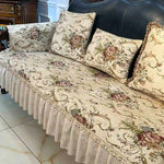 Canapé élégant avec motif floral imprimé, coussins assortis et jupe de canapé en dentelle, créant une atmosphère chaleureuse et raffinée dans une pièce de style traditionnel.