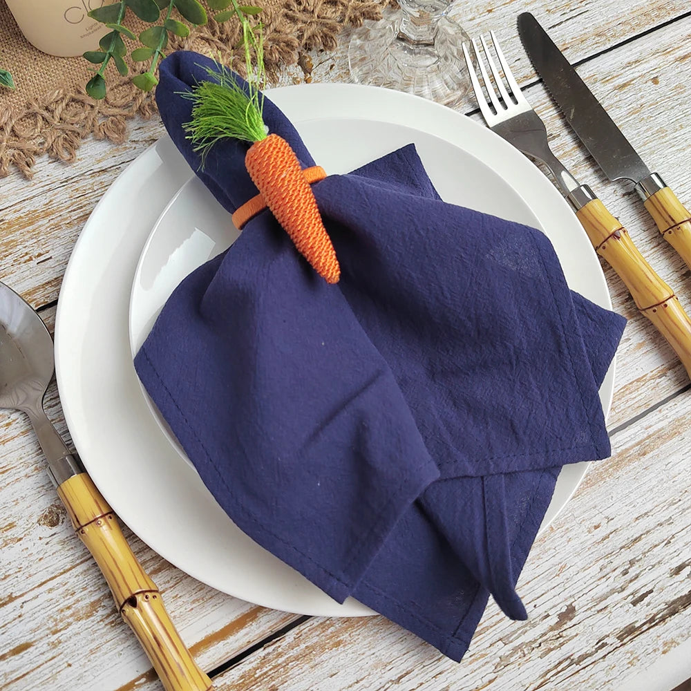 Une décoration de table élégante avec des serviettes de table bleu marine et un accent de carotte orange.