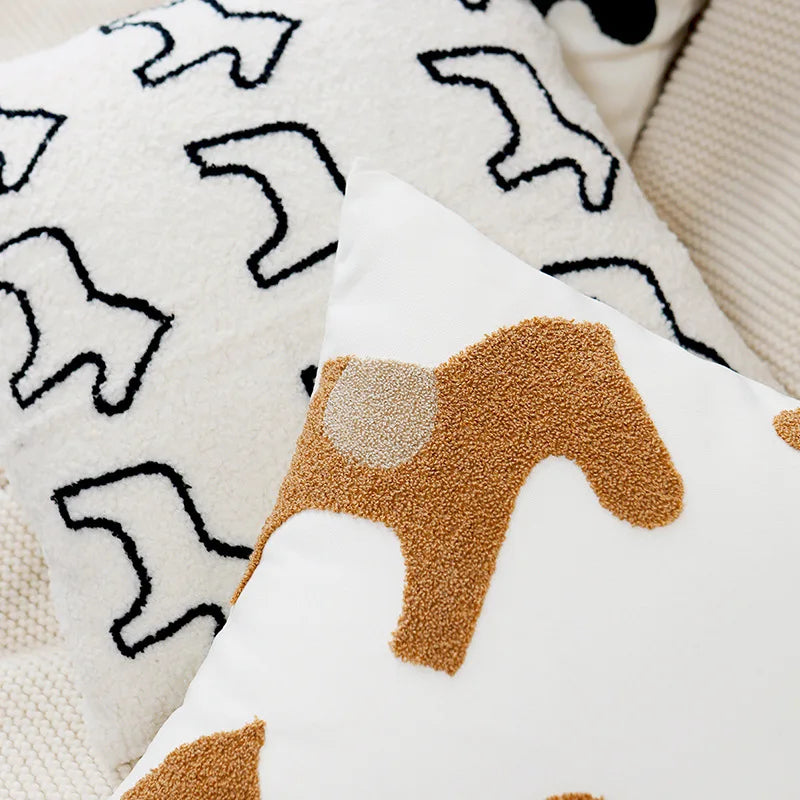 Motifs graphiques abstraits dans des tons de blanc et de brun sur un coussin en textiles doux et moelleux.