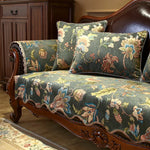 Cette image montre un canapé ancien en bois d'acajou avec un motif floral coloré sur les coussins.