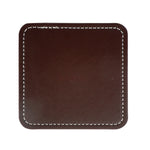 Image d'un carré en cuir marron foncé avec coutures blanches apparentes sur les bords, utilisé comme accessoire de bureau ou de décoration.