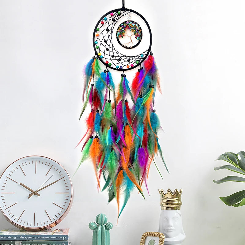Un attrapeur de rêves coloré et orné de plumes multicolores, suspendu contre un mur blanc avec des éléments décoratifs.