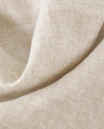 Un tissu en lin beige pâle, avec une texture tissée subtile et un aspect naturel et doux.
