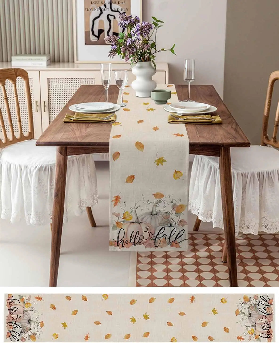 Une table à manger élégante avec une nappe aux motifs de feuilles d'automne, des assiettes blanches et des couverts dorés, le tout sur un fond de meuble en bois et de carrelage à motifs géométriques.
