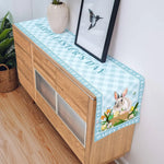 Un meuble en bois avec une jolie nappe à motifs de lapins et de fleurs de Pâques.