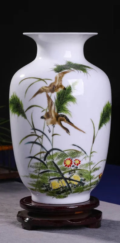 Vase en porcelaine blanche décoré de motifs de plantes et d'un oiseau en vol, sur un support en bois.