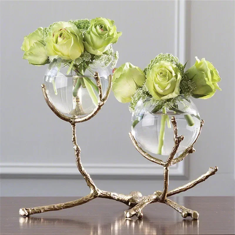 Vase en verre avec branches dorées et support laiton transparent sur table