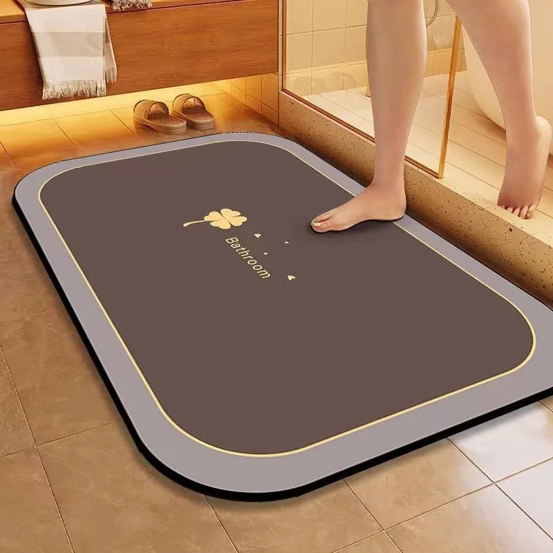 Un tapis antidérapant de couleur grise et gris foncé avec un motif de trèfle, posé sur un sol carrelé dans une salle de bain.