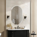 Ce miroir ovale élégant avec des appliques en cristal crée une ambiance chaleureuse et sophistiquée dans cette salle de bain contemporaine aux teintes neutres.