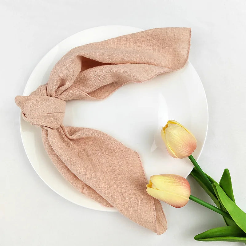 Gros plan sur des tulipes jaunes et roses entourées d'un foulard beige sur une assiette blanche.