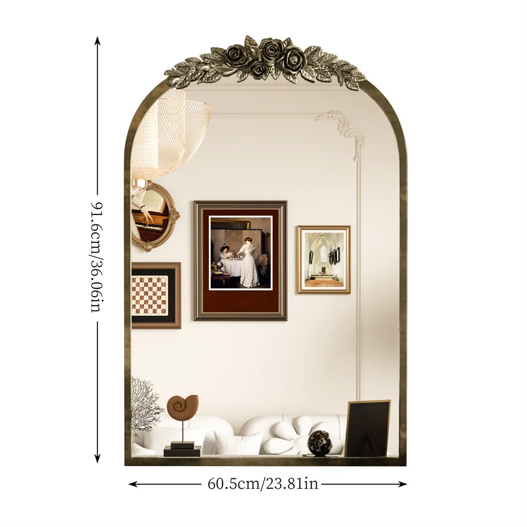 Miroir orné de fleurs de style vintage avec des cadres photos et des objets décoratifs.