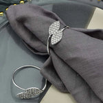 Un élégant anneau en argent orné de cristaux scintillants posé sur un tissu gris foncé.